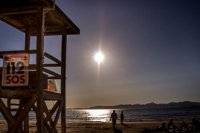 Lifeguard hut on beach against sky during sunset