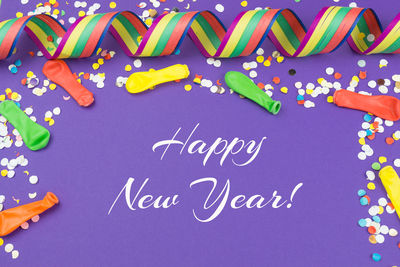 Happy new year text with confetti on purple background