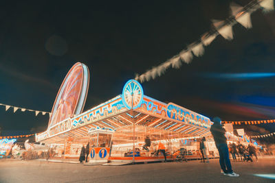 People in amusement park against sky at night