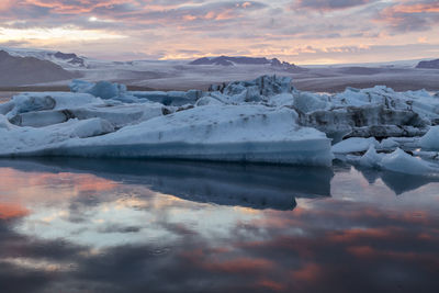 Scenic view of icebergs in lake against sky during sunset