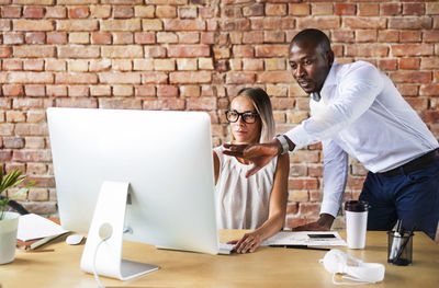 Two colleagues working together at desk in office