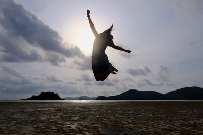 Silhouette man jumping in sea against sky