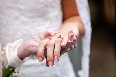 Cropped image of grandmother holding hands of bride