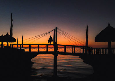 Silhouette people by sea against sky during sunset