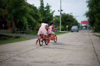 Rear view of woman riding bicycle on road