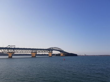 Bridge over sea against clear blue sky