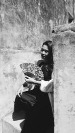 Woman looking away while sitting on wall