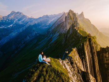 Man sitting on rock against mountains