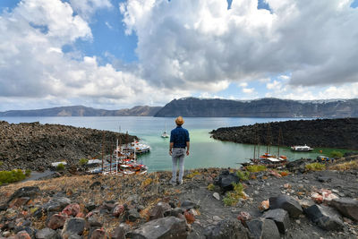 Rear view of man standing on rocks against sky