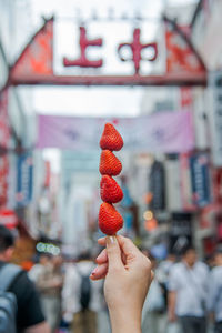 Close-up of hand holding strawberries in city