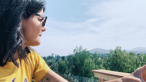 Portrait of woman looking at mountains against sky