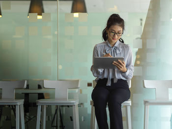 Cheerful businesswoman using digital tablet while sitting at cafe