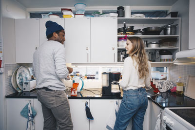 Happy young roommates cooking in kitchen