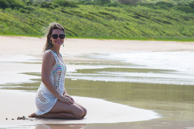 Portrait of young woman kneeling at beach in fernando de noronha