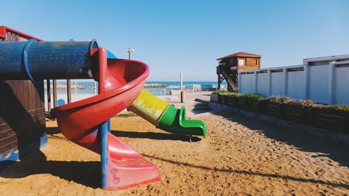 Slides on sand at beach against sky