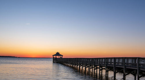 Pier over sea against sky during sunset