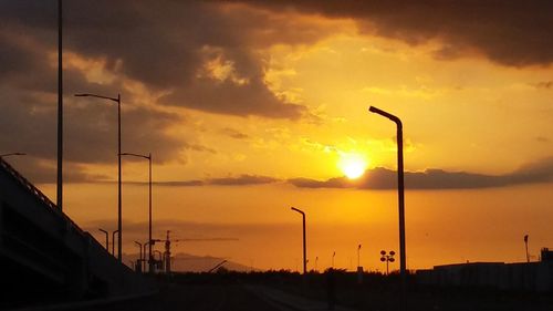 Silhouette road against dramatic sky during sunset