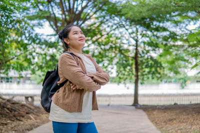 Young woman standing against trees