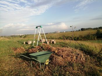 Deck chairs on field against sky