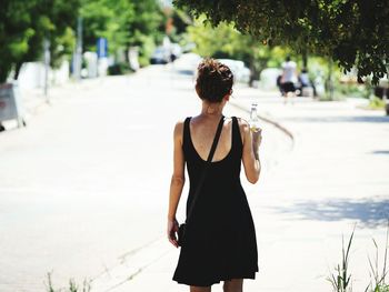 Rear view of woman standing on footpath