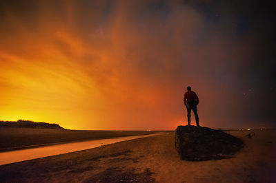 Silhouette man standing at beach against sky during sunset