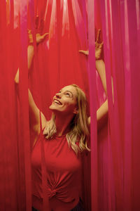 Smiling young woman standing against curtain