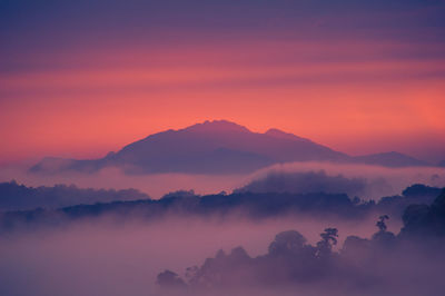 Scenic view of silhouette mountains against orange sky