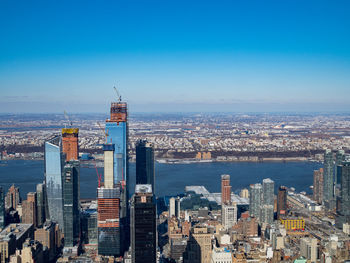 Aerial view of buildings in city against blue sky