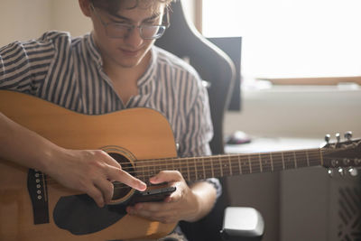 Midsection of man playing guitar