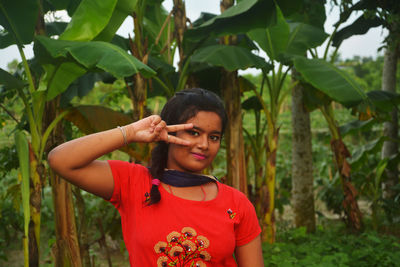 Portrait of young woman standing by leaves