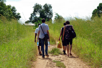 Rear view of people walking on grassland