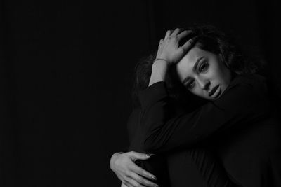 Portrait of beautiful young woman against black background