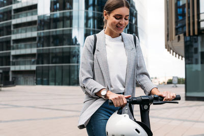 Smiling young woman with bicycle in city