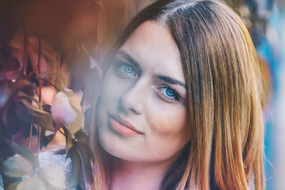 Close-up portrait of young woman by plants