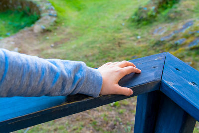Cropped hand of person on blue wooden railing