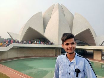 Smiling young man standing against built structure