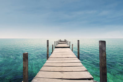 Wooden pier over sea against sky