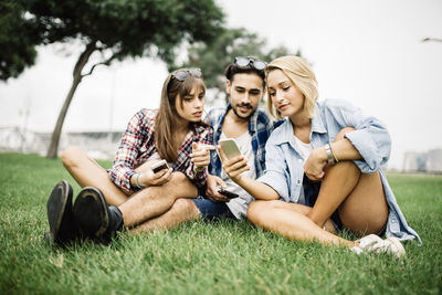 Portrait of happy friends sitting on grass