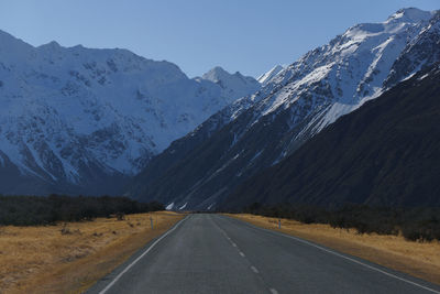 Road by mountains against clear sky