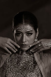 Portrait of woman wearing make up against black background