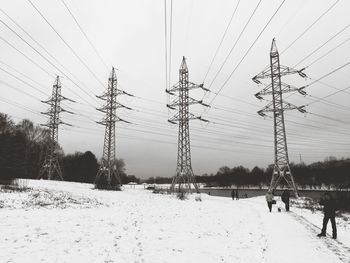 Electricity pylon on field against sky during winter