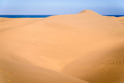 Sand dunes in desert against clear sky