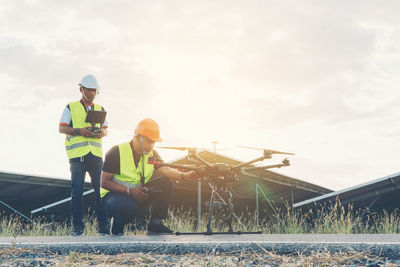 People working on motorcycle against sky