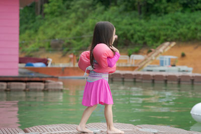 Rear view of woman standing by swimming pool