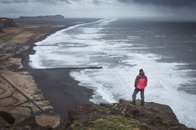 Rear view of man standing on rock at beach