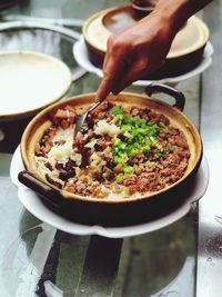 Cropped hand serving food in utensil on table