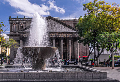 Fountain in city against sky