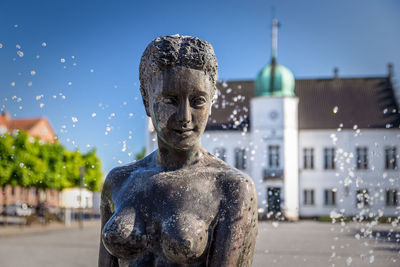 Statue against buildings in city against sky