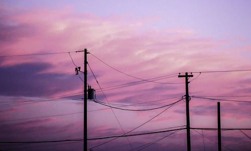 Low angle view of electricity pylon against dramatic sky