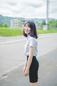 Portrait of smiling young woman standing on road